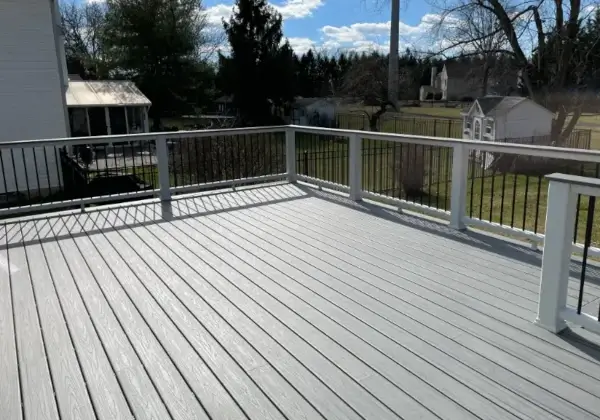Spacious outdoor deck with white railing and trees.