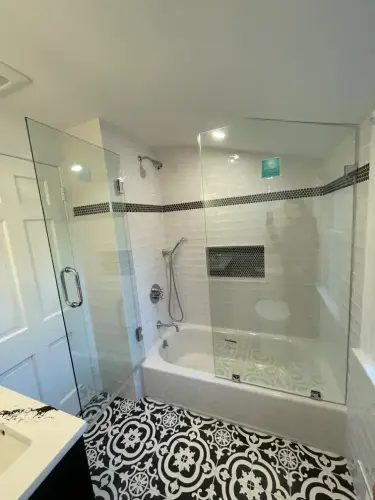 Modern bathroom with glass shower and patterned floor tiles.