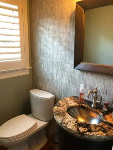Modern bathroom with granite countertop and mirror.