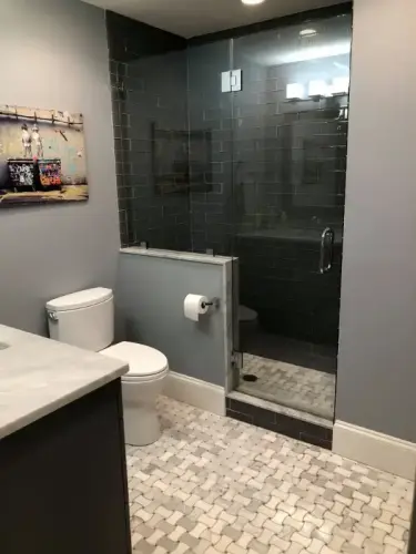 Modern bathroom with glass shower and tiled floor.