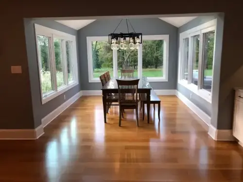 Bright dining room with large windows and chandelier.
