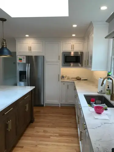 Modern kitchen with white cabinets and wood floor.