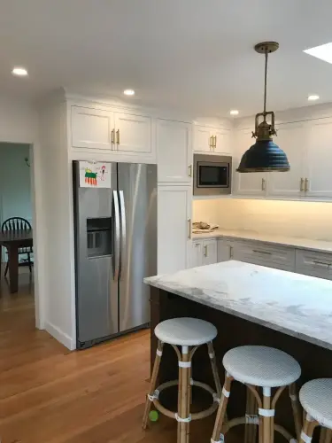Modern kitchen with marble island and stainless fridge.