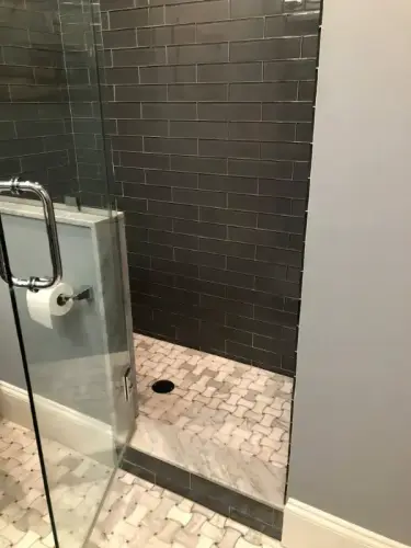 Shower with dark tiles and glass door.