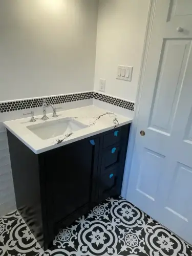 Black vanity with marble countertop in bathroom.