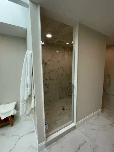 Elegant marble bathroom with glass shower door.