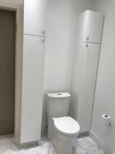 Modern bathroom with white cabinets and toilet.