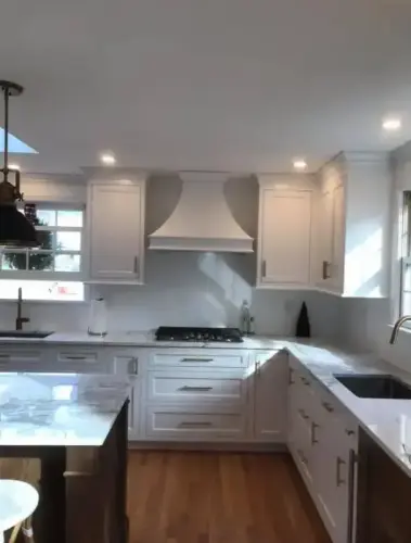 Modern kitchen with white cabinets and marble countertops.