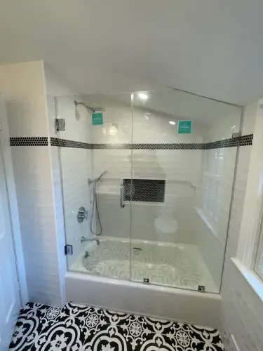 Modern shower with glass door and decorative tiles.