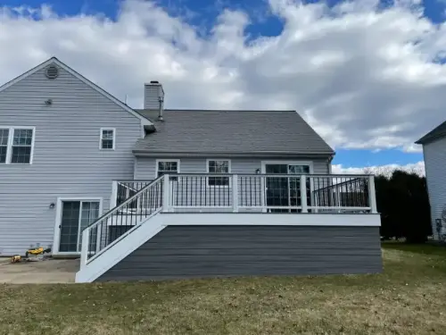 Large gray house with elevated wooden deck.