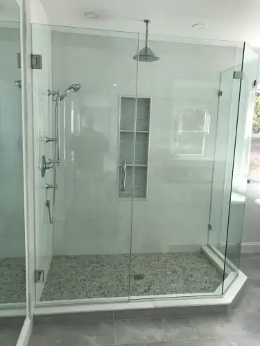 Modern glass-enclosed walk-in shower with stone floor