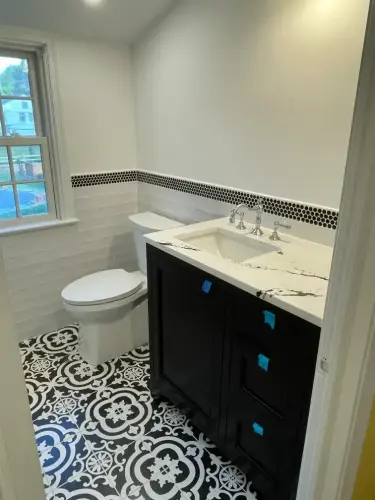 Modern bathroom with patterned floor tiles and black vanity.
